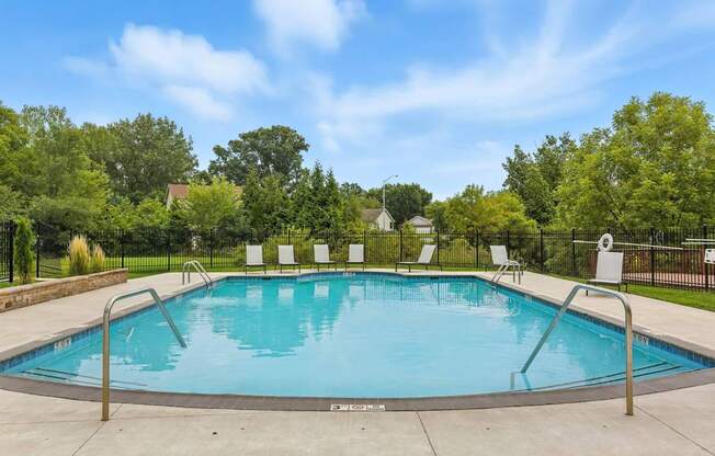 A swimming pool surrounded by trees and chairs.