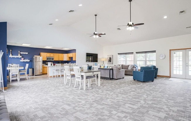 Wide view of the clubhouse at Williamsburg Park with dining table, TV lounge, and community kitchen in the back