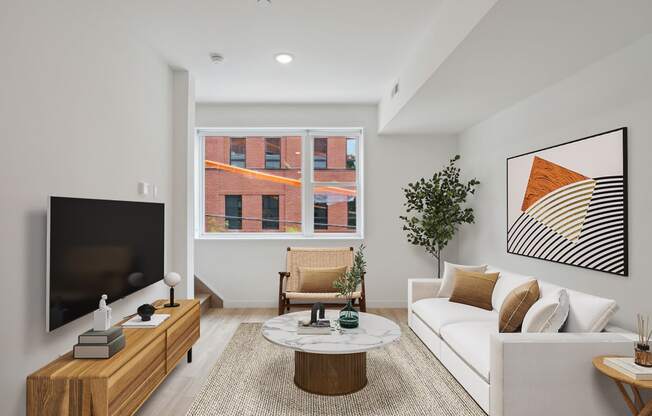 Modern living room captured from a high angle, highlighting a white sofa, a round coffee table, and a smart TV setup, with a glimpse of the dining area in the distance.