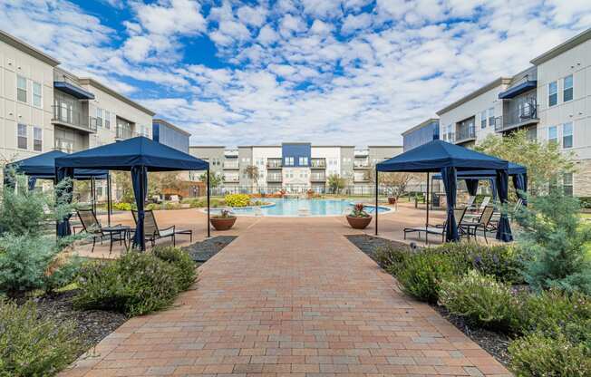 a courtyard with umbrellas and chairs and a swimming pool