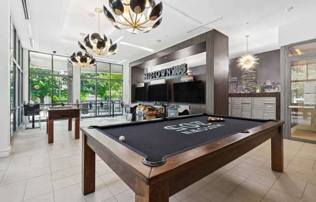 a games room with a pool table and two televisions