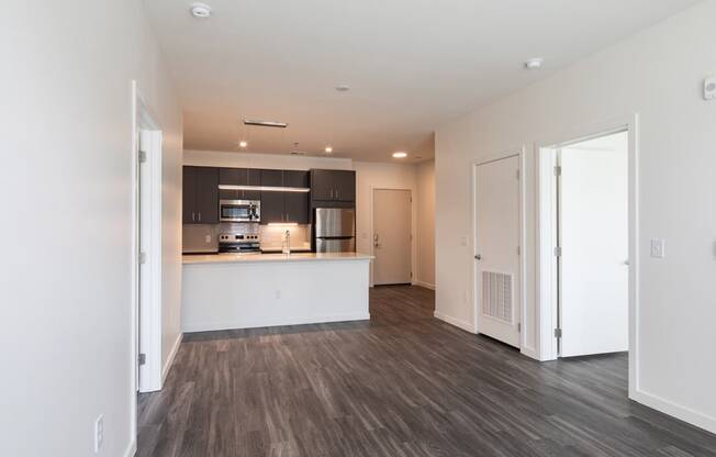 a living room with a kitchen and a door to a hallway