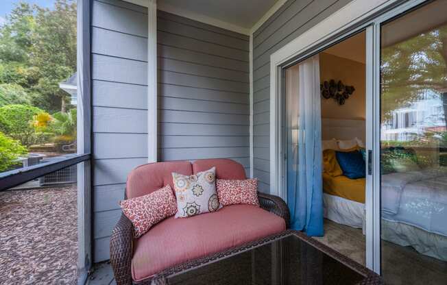 a covered porch with a pink chair and a glass coffee table