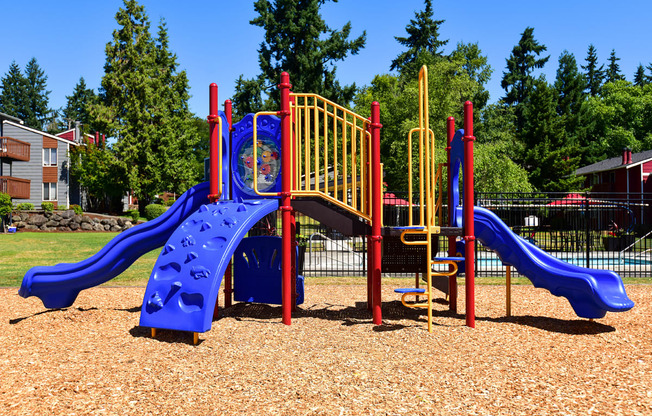a playground with a blue and red slide and monkey bars