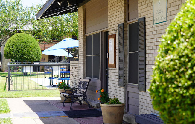 the front porch of a house with a bench and a patio umbrella