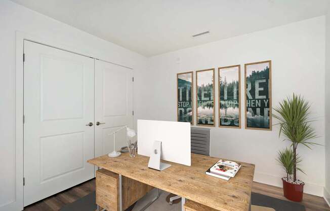 A room with a wooden desk and a potted plant.