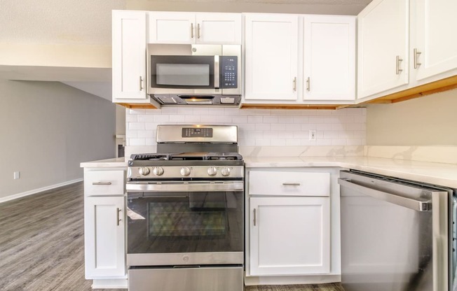 a kitchen with white cabinets and stainless steel appliances