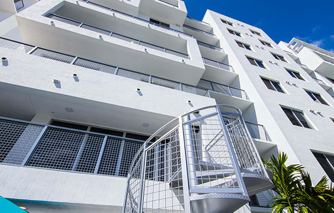 a white apartment building with a spiral staircase in front of a blue sky at Saba Pompano Beach, Pompano Beach, 33062