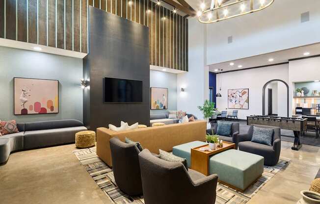 A modern living room with a variety of seating options and a flat screen TV mounted on the wall.
