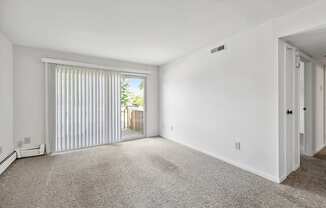 an empty living room with a sliding glass door to a balcony