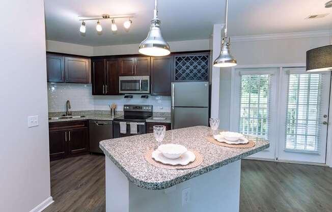 A kitchen with a granite countertop and dark brown cabinets.