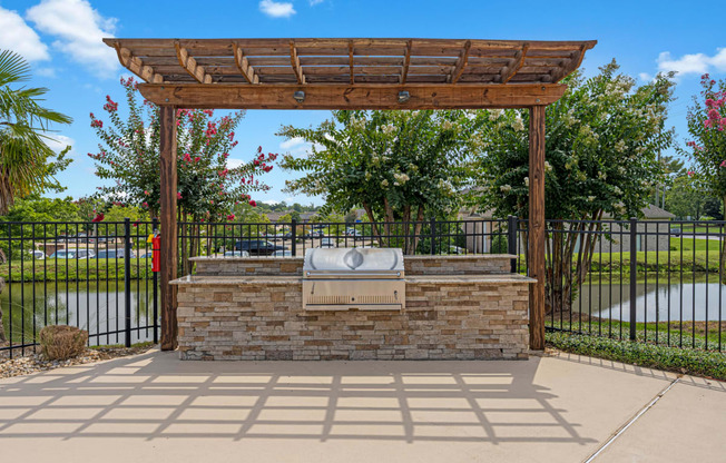 a patio with a stone fireplace and a wooden pergola