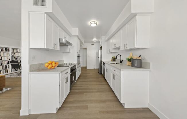 a long white kitchen with white cabinets and counter tops