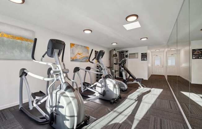 A gym with exercise equipment and a mirror on the wall.