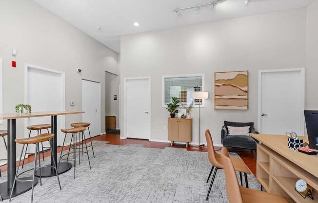 A room with a desk, chairs, and a potted plant.