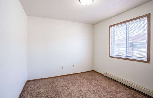 A room with a window and carpeted floor.