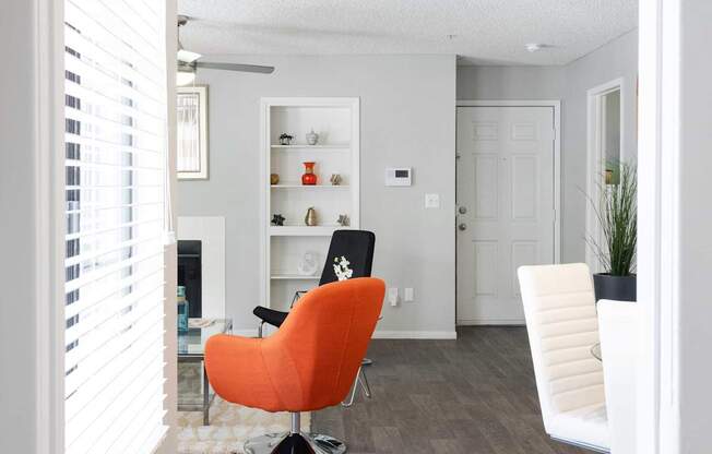 a living room with an orange chair and a wood floor