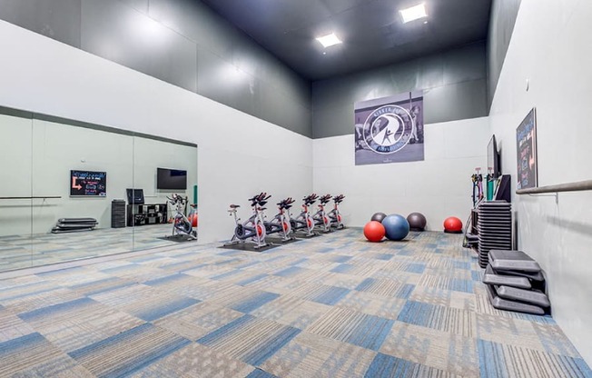 A gym with exercise equipment and a blue carpet.