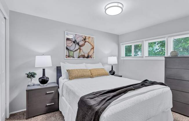 a bedroom with a white bed and two windows