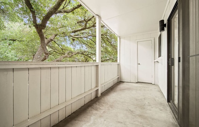 a long porch with a door and trees in the background