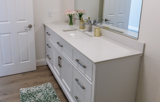 a bathroom with white cabinets and a white sink and mirror