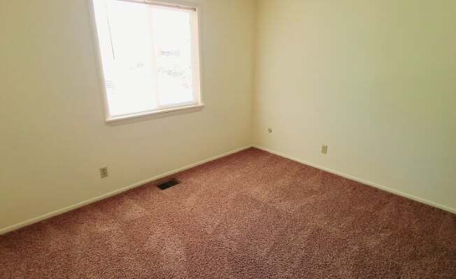 A room with a carpeted floor and a window.