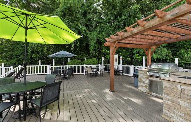 A wooden deck with a table and chairs and a grill.