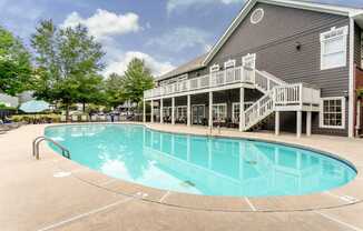A large outdoor swimming pool with a deck and stairs leading to a building.