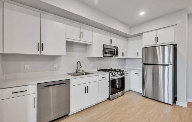 A modern kitchen with white cabinets and stainless steel appliances.