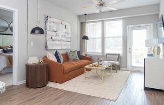 a living room with a brown couch and a ceiling fan