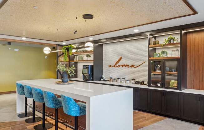 A modern kitchen with a white counter and blue chairs.