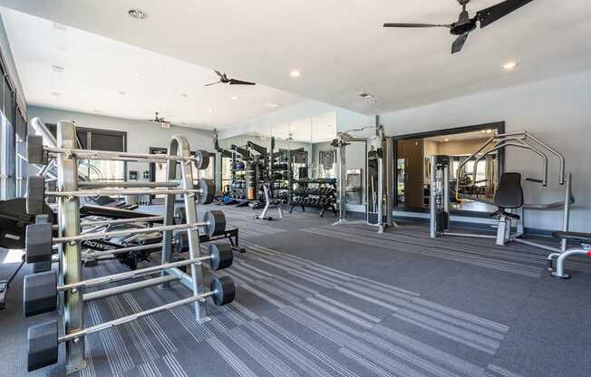 A spacious gym with a variety of equipment and a ceiling fan.