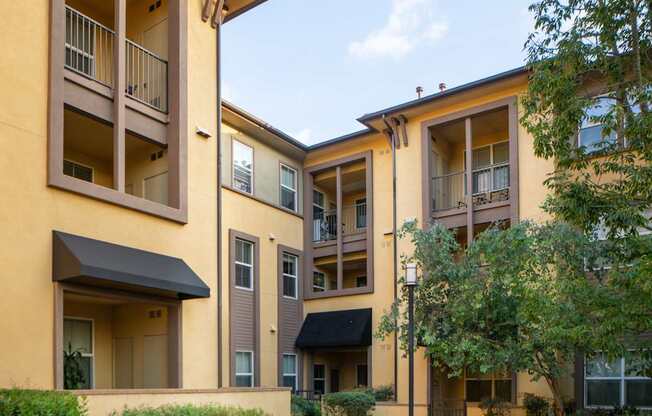 A building with a yellow facade and a balcony on the second floor.
