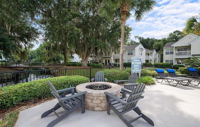 A fire pit surrounded by chairs in a sunny outdoor setting.