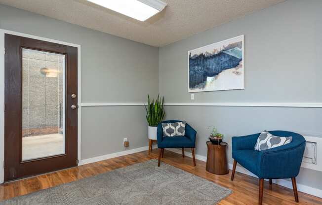 Leasing office entry with two blue chairs, grey area rug and view of front door.