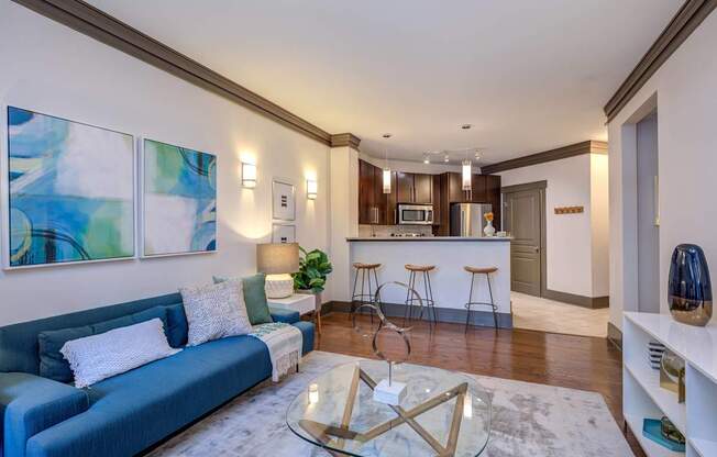 A modern living room with a blue couch and a glass coffee table.