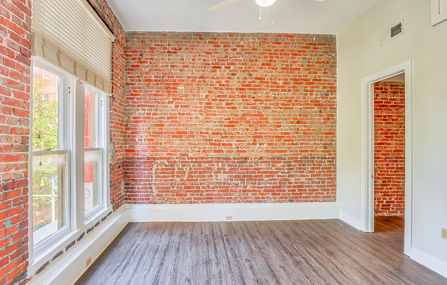an empty room with hardwood floors and a brick wall