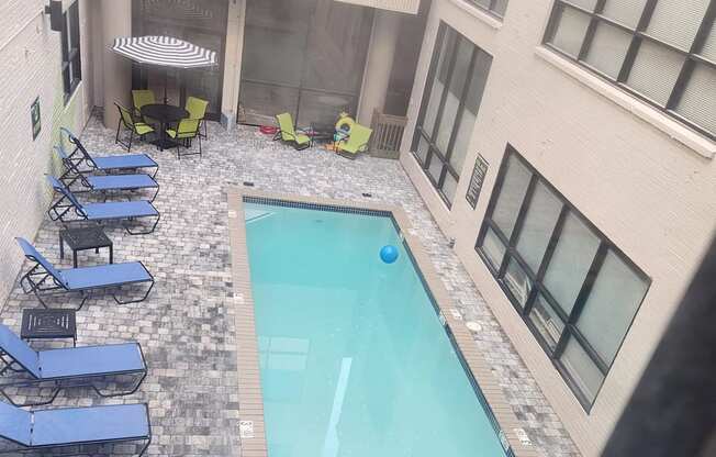 A pool area with blue chairs and a stone wall.