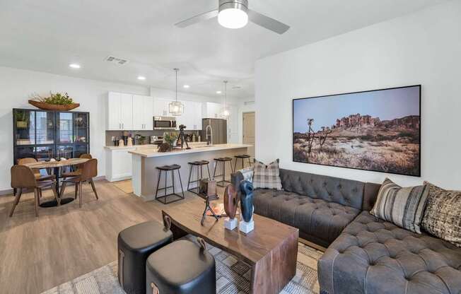 A modern living room with a large couch, a dining table, and a kitchen area in the background.