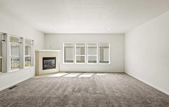 an empty living room with a fireplace and windows