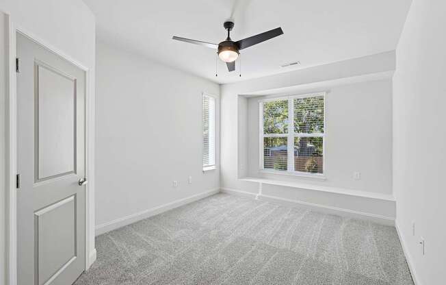 A room with a ceiling fan and a window with blinds.