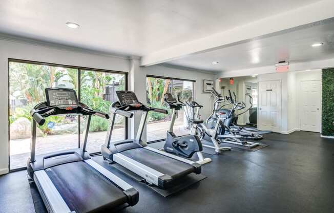 Fitness center in Fusion Warner Center apartments in Woodland Hills with cardio machines facing out large sliding glass windows.