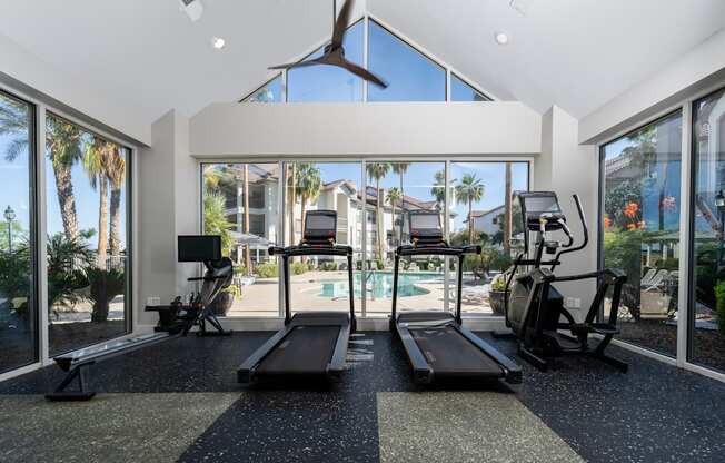 A gym with treadmills, exercise bikes, and a fan.