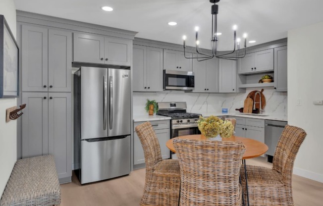 a white kitchen with stainless steel appliances and a table and chairs