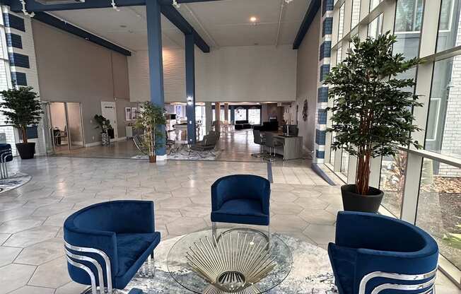 a large lobby with blue chairs and a glass table