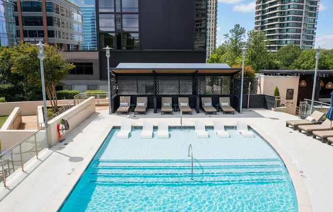 A large outdoor swimming pool with a diving board and lounge chairs.