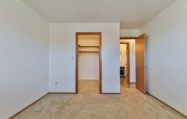 an empty living room with a closet and a hallway to a bedroom