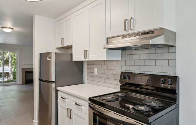 an empty kitchen with white cabinets and a stove and refrigerator