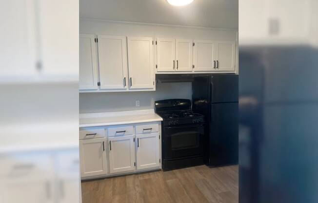 a kitchen with white cabinets and a black stove and refrigerator