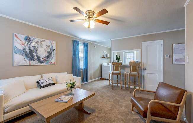 A living room with a white couch, a brown leather chair, and a wooden coffee table.